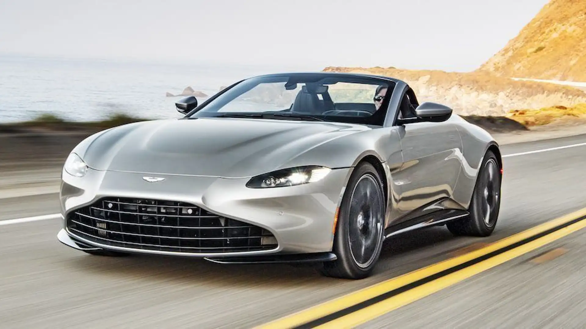 A front view of a gray Aston Martin Vantage Roadster on a country road.